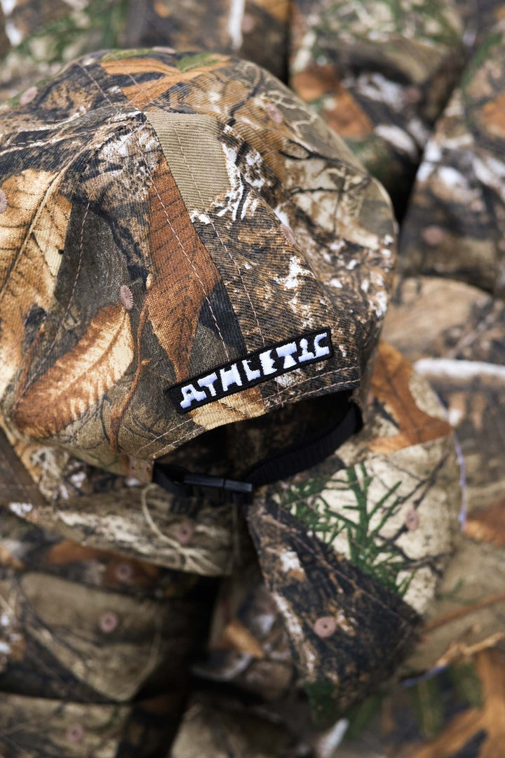 The Realtree Realness Cap is a versatile, unstructured 6-panel hat featuring a unique camo pattern that varies slightly with each cap, adding individuality to your gear. Designed in collaboration with Kyle Kelley, it includes a soft, regular-length bill and no top button, ensuring comfort under a helmet. Crafted in the USA, this hat is perfect for everyday wear and is easily packable for on-the-go adventures