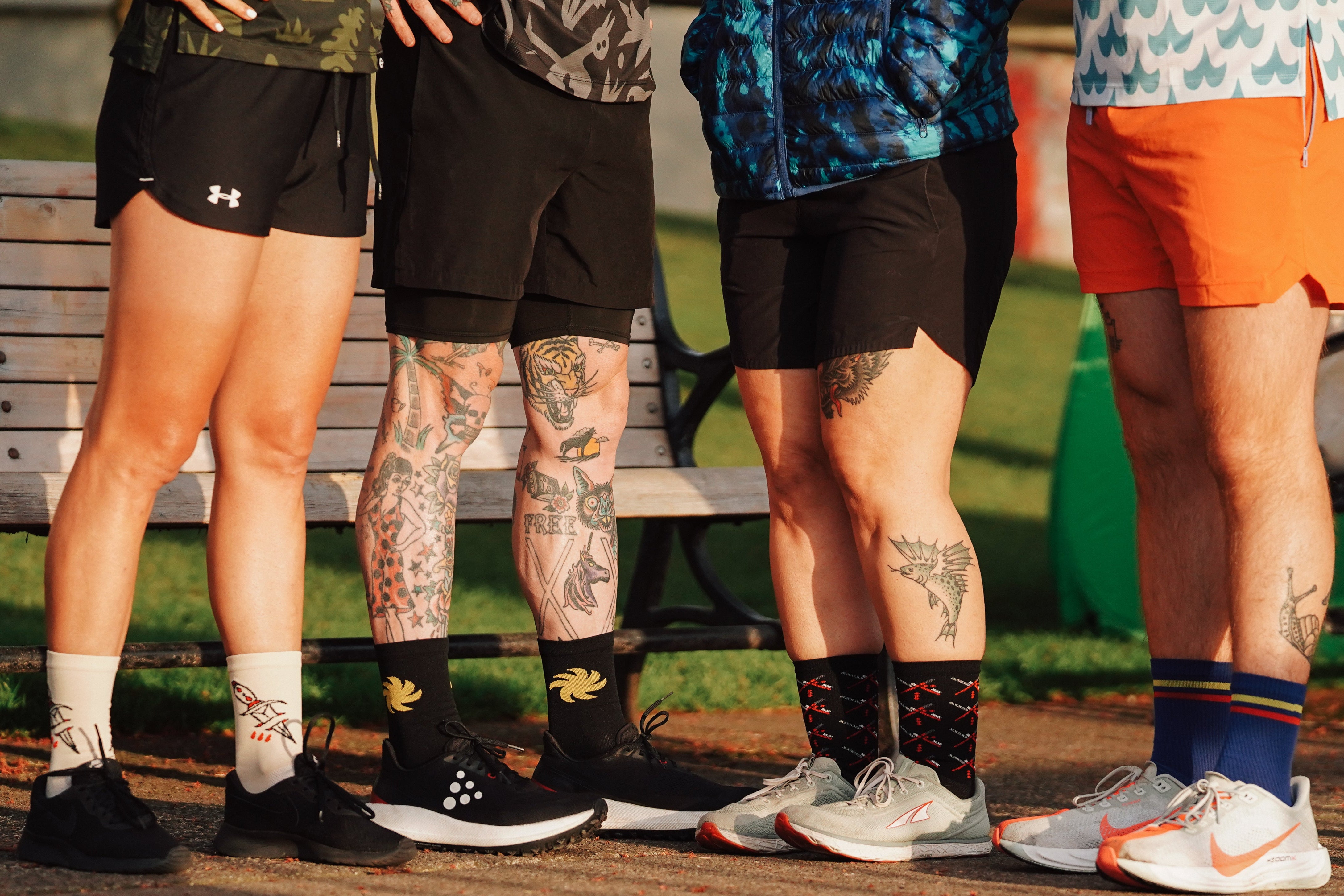 Four people standing on a path with their legs and feet visible, wearing socks and shoes.