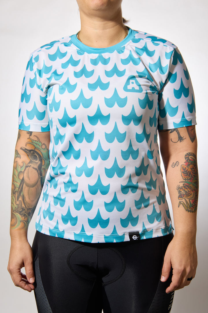 The Women's Mustache Tech Tee is a short-sleeve, moisture-wicking shirt designed for mountain biking, running, or road cycling. Made in the USA by Endo Customs, this versatile performance top adapts seamlessly to your ride or run. Constructed from lightweight, breathable Italian fabric, it features a split side seam at the hem to accommodate lower body movement