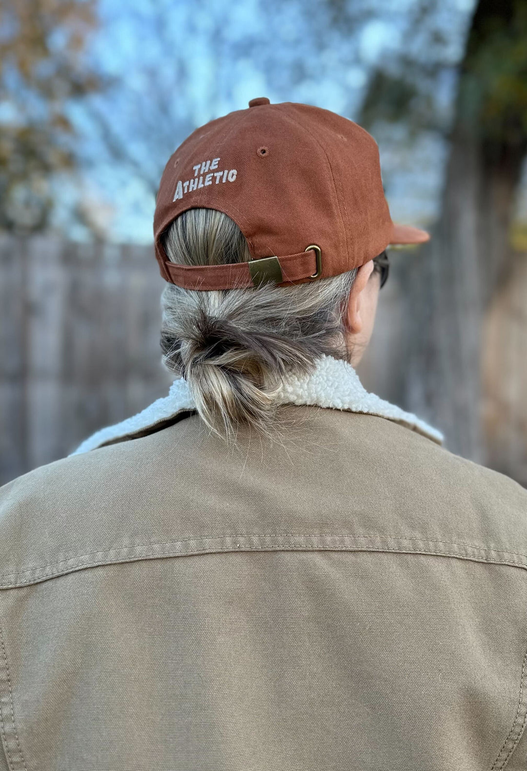 The Athletic Armadillo Hat in rust features an unstructured 6-panel design with an adjustable fabric strap and brass metal clasp. Embroidered with a stylized armadillo logo, this hat combines comfort and style for everyday wear