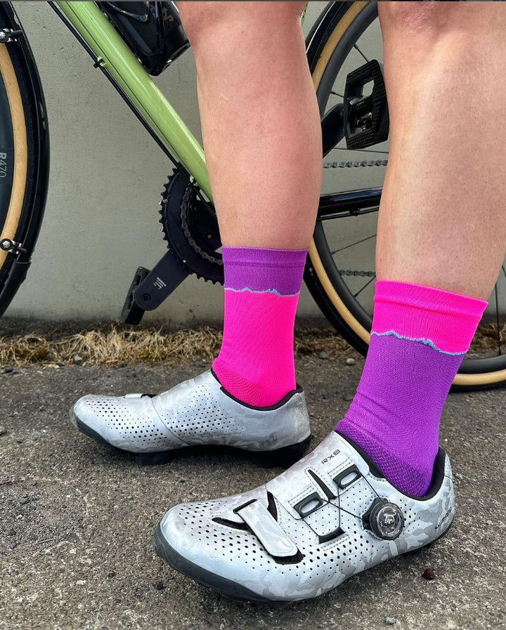 The Elevation Socks – Hood to Coast Edition are designed to commemorate the iconic Hood to Coast Relay, featuring a design that mirrors the elevation profile of the course from Wy'East to the Pacific Ocean. These socks are crafted for versatility, suitable for running, walking, hiking, or cycling. They offer a medium compression cuff for support and are made from a blend of 60% nylon, 39% recycled polyester, and 1% Lycra, ensuring both comfort and durability. Machine washable for easy care