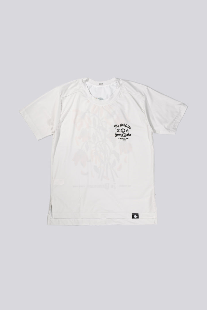 The Women's In Memoriam Short Sleeve Tech Tee is a bright white, short-sleeve shirt featuring a chest decal and a flower design across the back. Ideal for running, cycling, or cross-training, this tee pairs beautifully with black El Sol socks or gold Death Palm designs. Crafted in California from Italian fabrics by Endo Customs, it offers both style and performance for active individuals