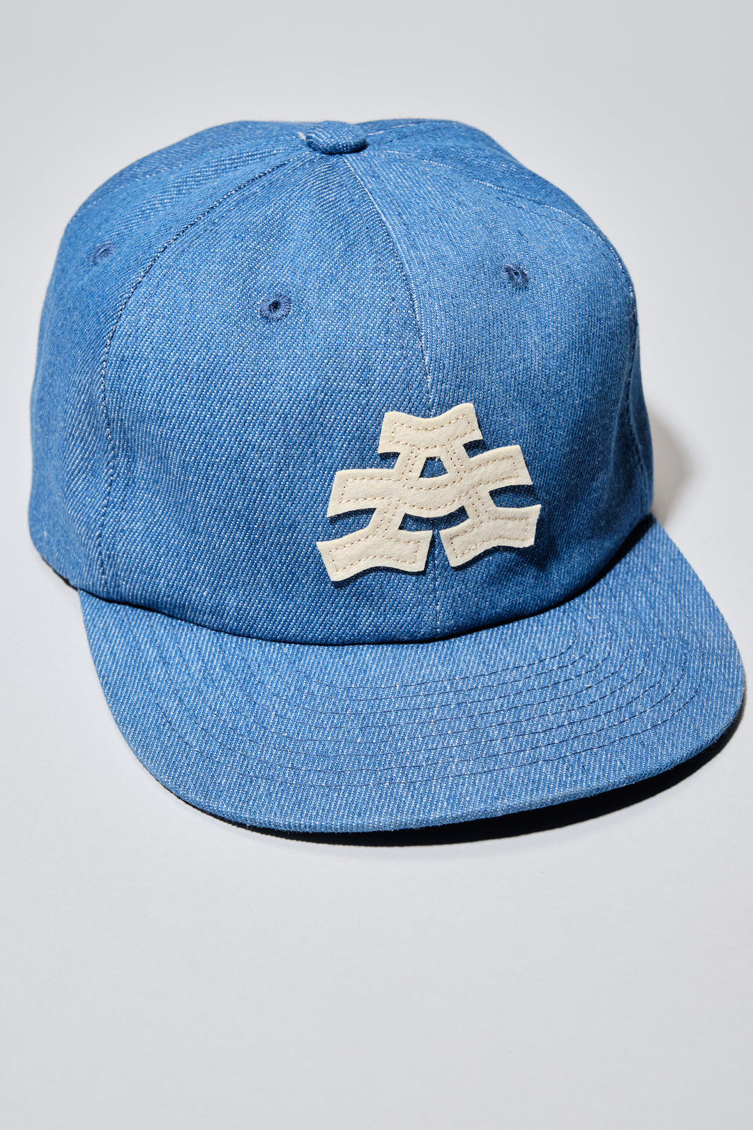 The Athletic Wavy A Denim Hat is a 100% cotton denim cap featuring the embroidered "Wavy A" logo, symbolizing The Athletic's blend of past and future. Designed in collaboration with Young Jerks, this hat offers a timeless, denim aesthetic suitable for various off-bike activities