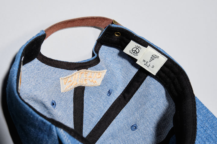 The Athletic Wavy A Denim Dad Hat is a 100% cotton denim cap featuring the embroidered "Wavy A" logo, symbolizing The Athletic's blend of past and future. Designed in collaboration with Young Jerks, this hat offers a timeless, denim aesthetic suitable for various off-bike activities