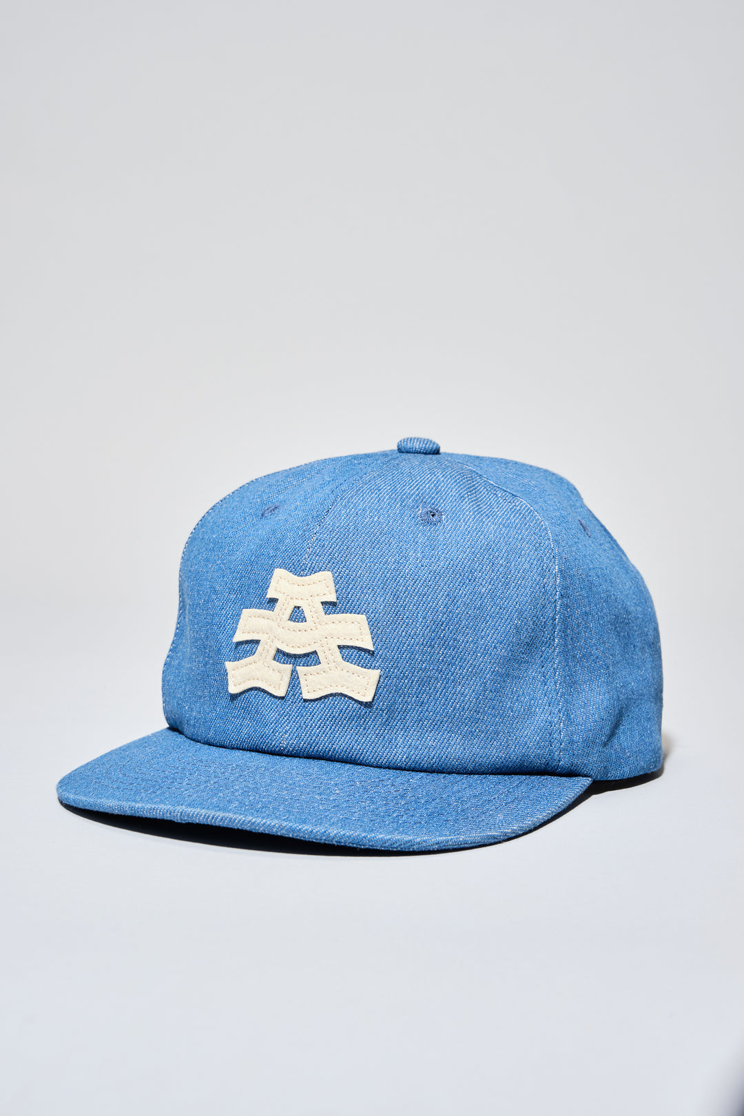 The Athletic Wavy A Denim Dad Hat is a 100% cotton denim cap featuring the embroidered "Wavy A" logo, symbolizing The Athletic's blend of past and future. Designed in collaboration with Young Jerks, this hat offers a timeless, denim aesthetic suitable for various off-bike activities