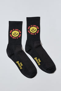 Smiley face socks with "Sure, I like fun" caption. Socks are black.