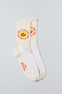 Smiley face socks with "Sure, I like fun" caption. Socks are oatmeal colored.